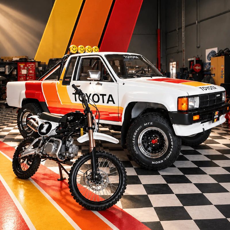 The black Buscadero pit bike parked in front of the striped white Toyota in a garage