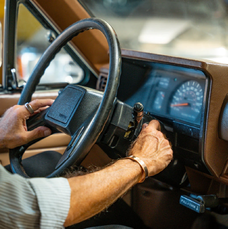 A pair of hands on the brown steering wheel with the gauge cluster lit up behind it