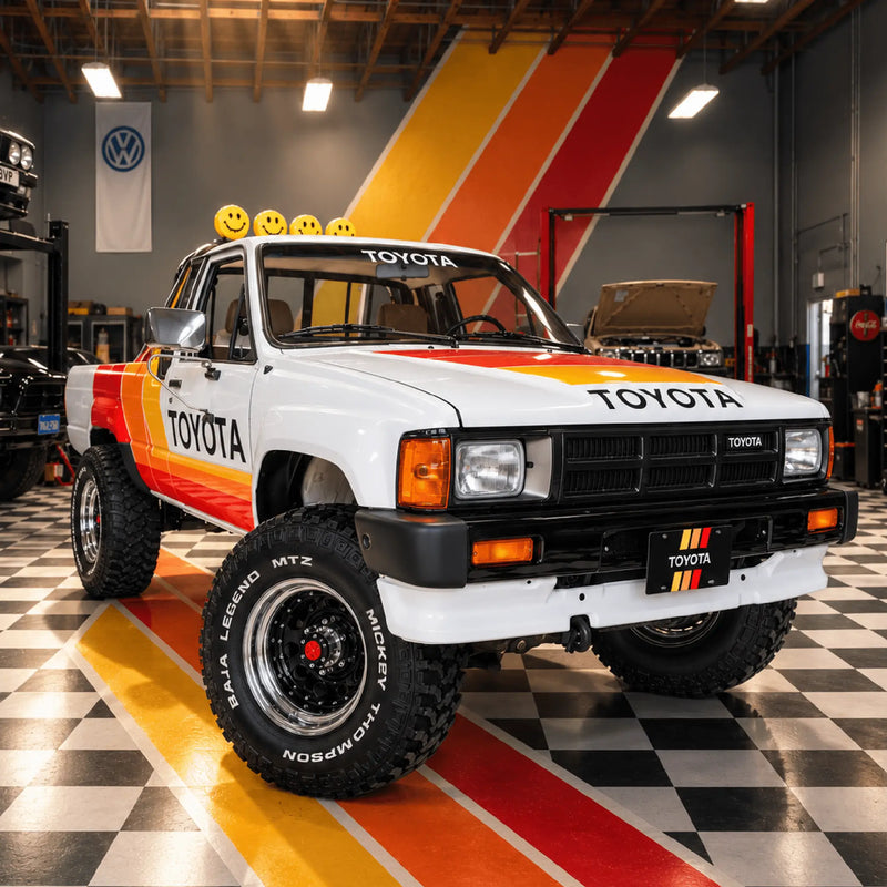 The white Toyota from the front three-quarter angle in a garage with stripes painted on the wall behind it