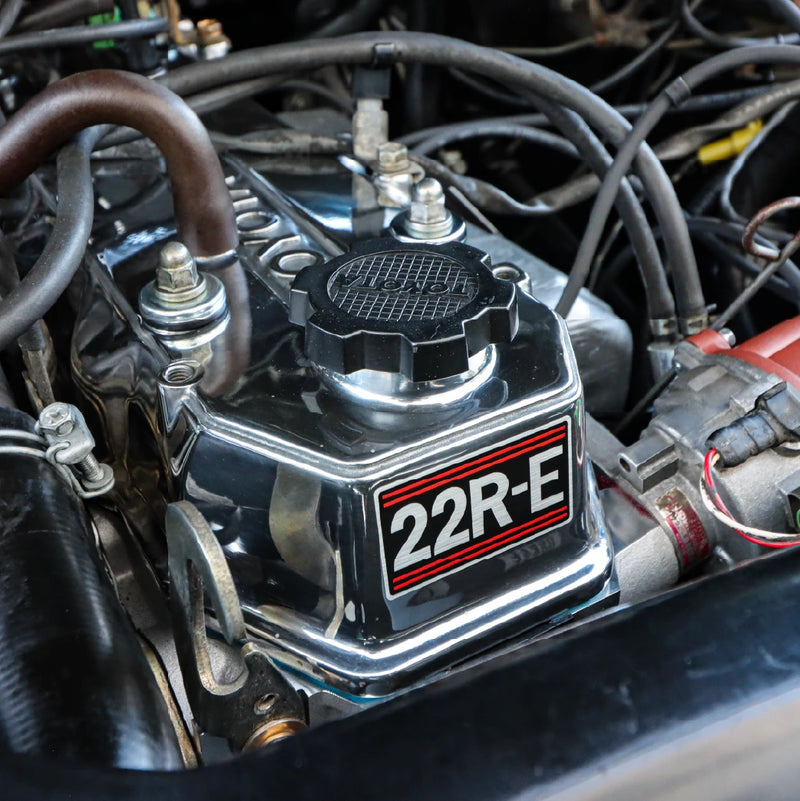 Close-up of the 22R-E badge on the chrome valve cover inside the engine bay